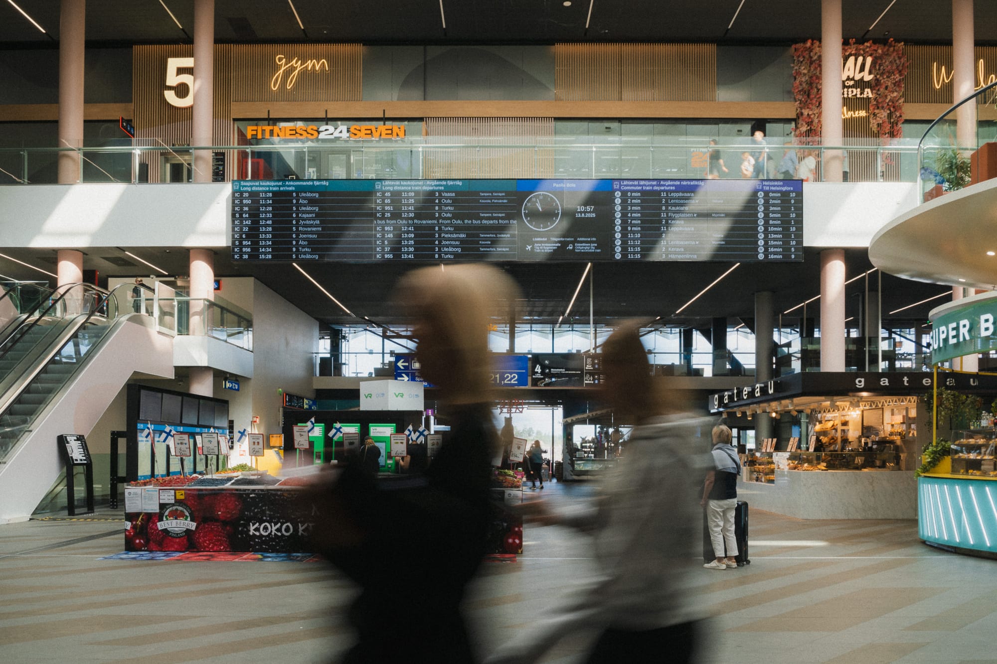 Innenaufnahme vom Bahnhof mit Ständen, Geschäften und Menschen