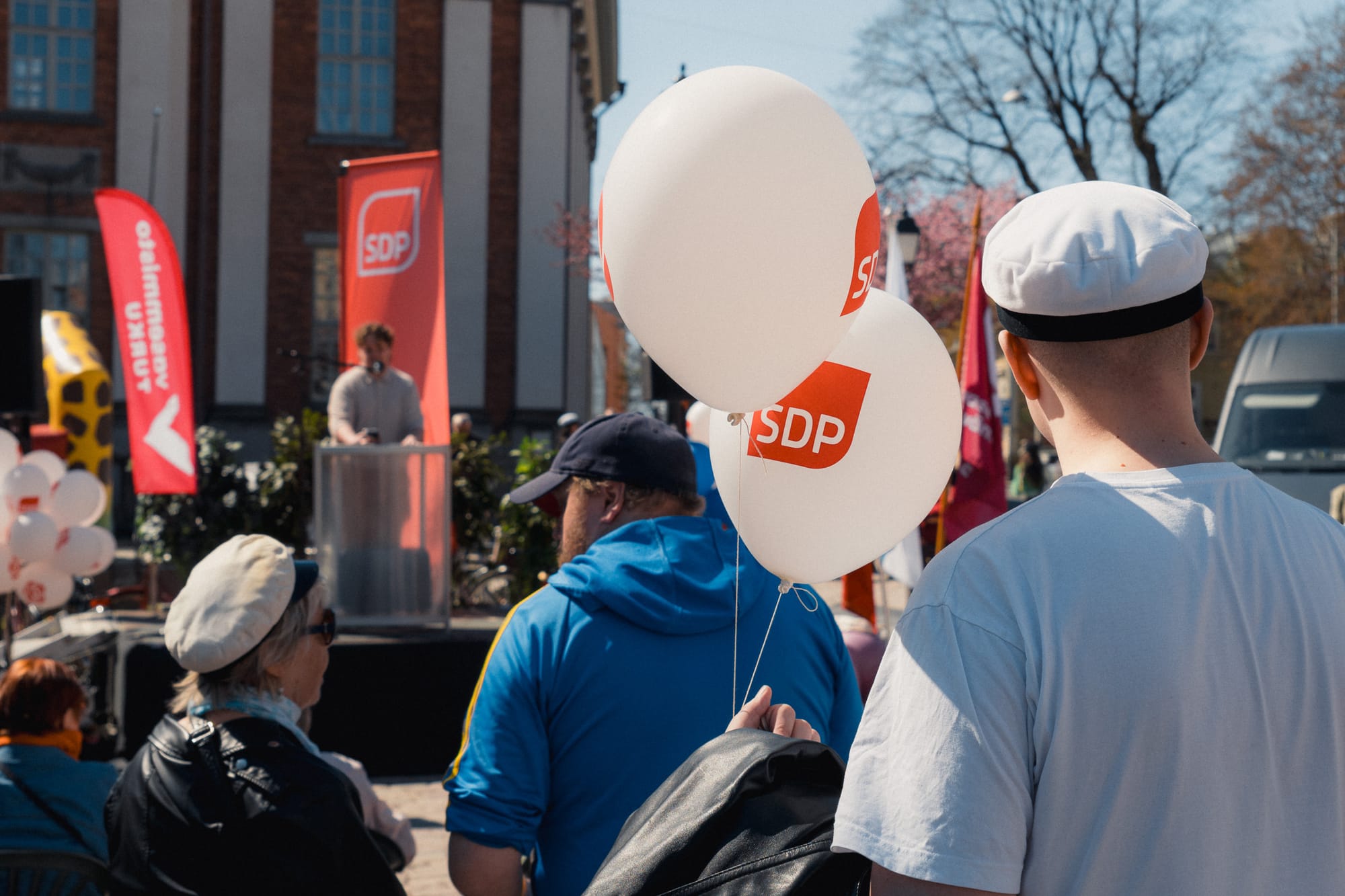 Person mit Luftballons der Partei SDP, im Hintergrund ein Redner
