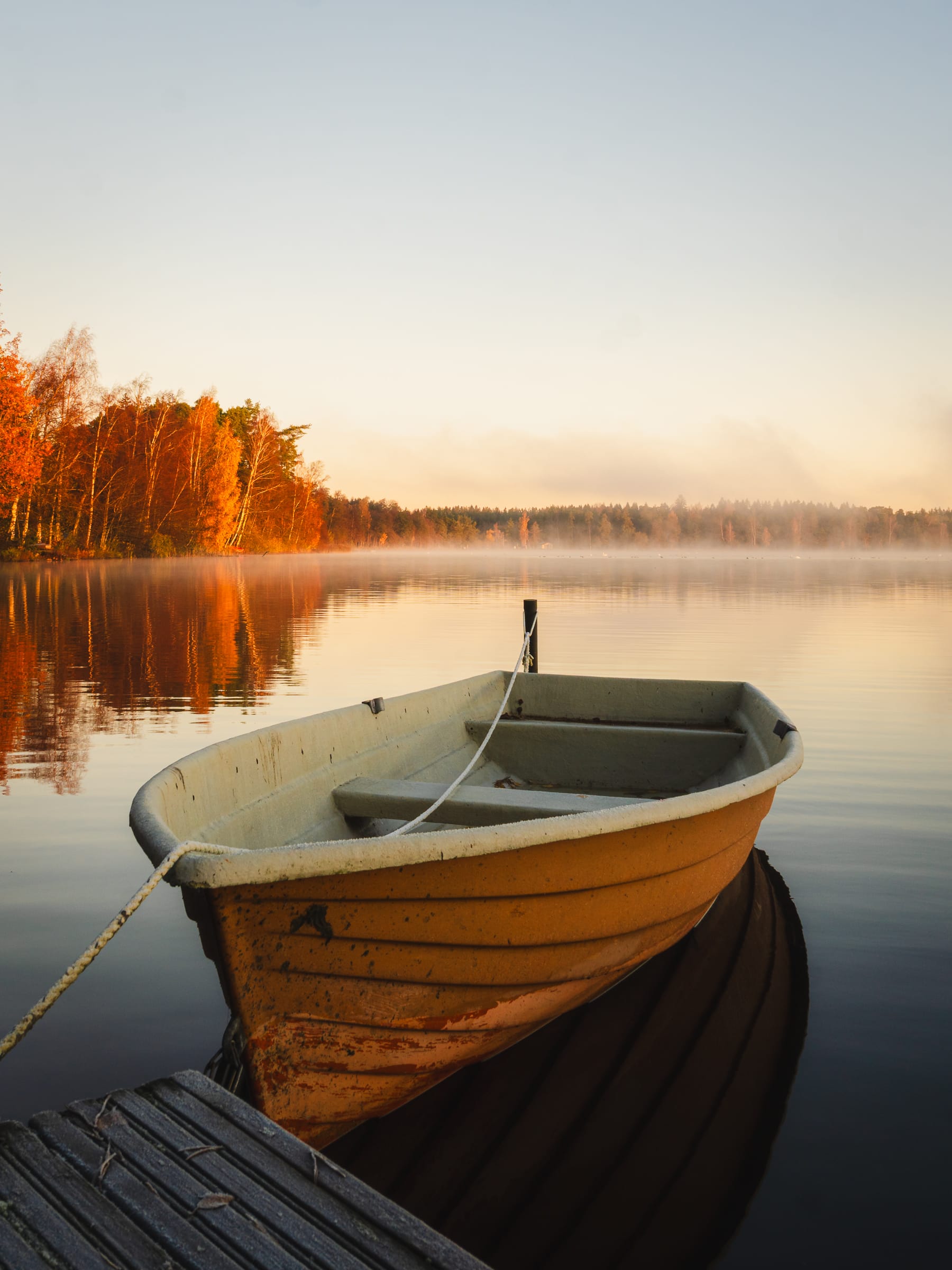 Boot am Steg an einem Herbstmorgen am See