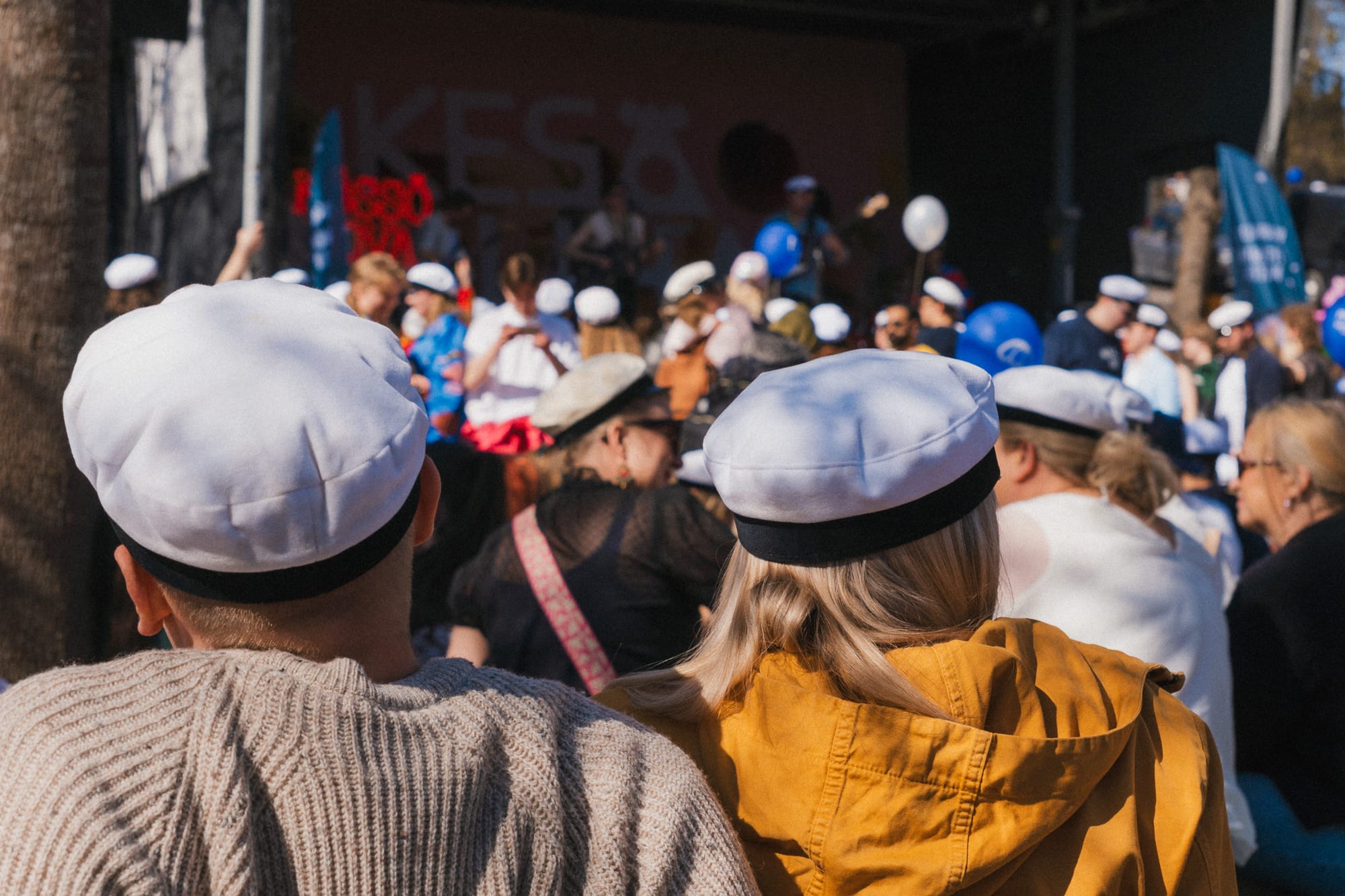 Menschen mit Studentenmütze vor einer Bühne